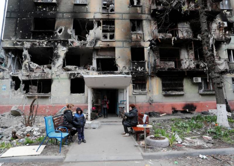 Local residents gather outside a residential building heavily damaged during Ukraine-Russia conflict in the southern port city of Mariupol, Ukraine April 21, 2022.