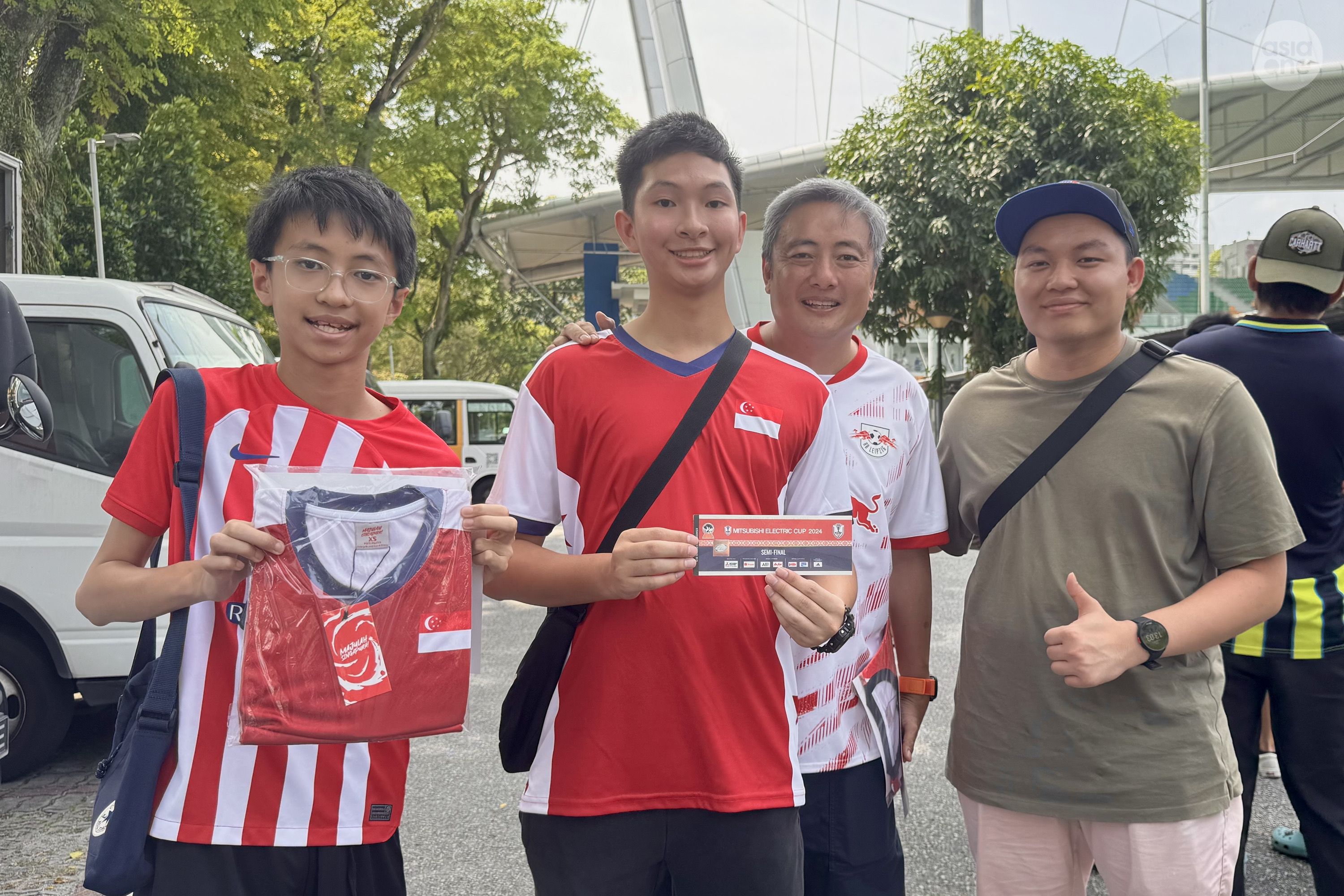 Lions fan Lau with his sons and a friend with the football merchandise and tickets they secured for the semi-final match against Vietnam to be played on Dec 26. 