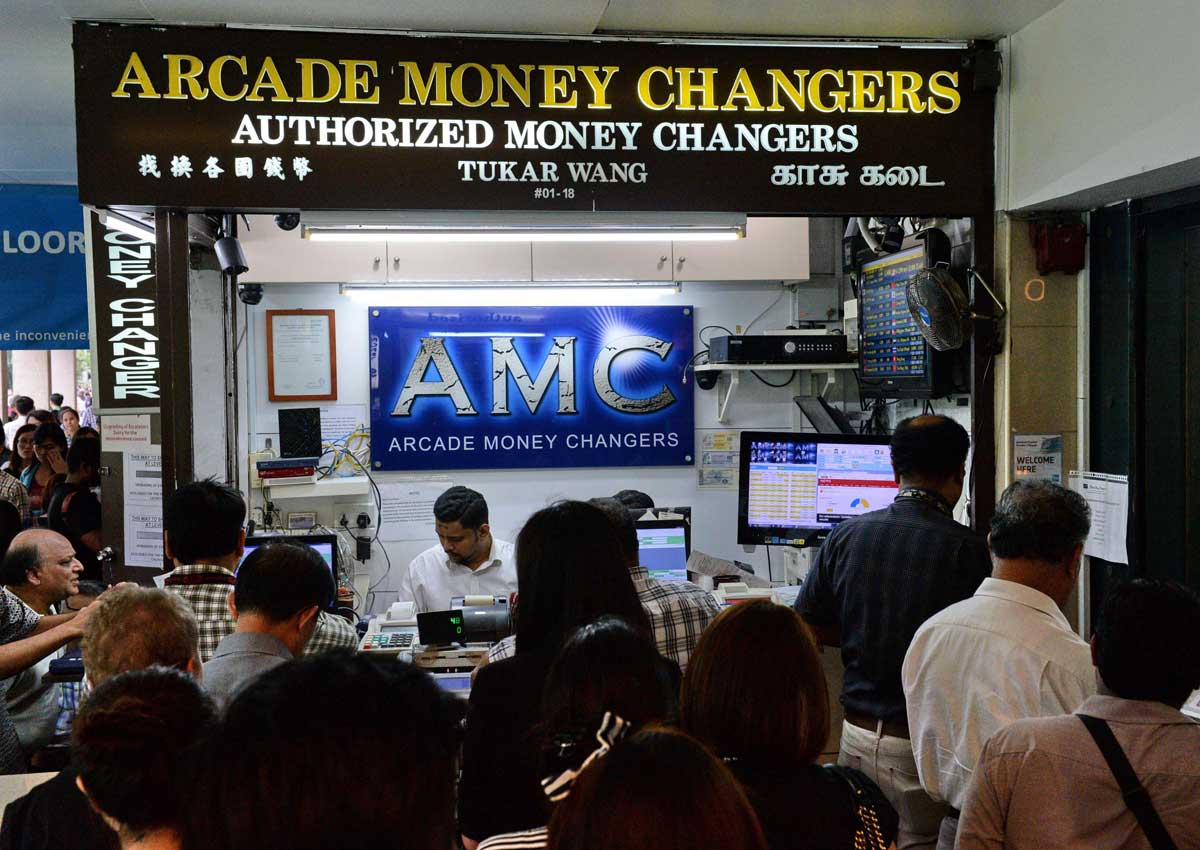 A long queue of people waiting to exchange their Singapore dollars for pound sterling at a money changer